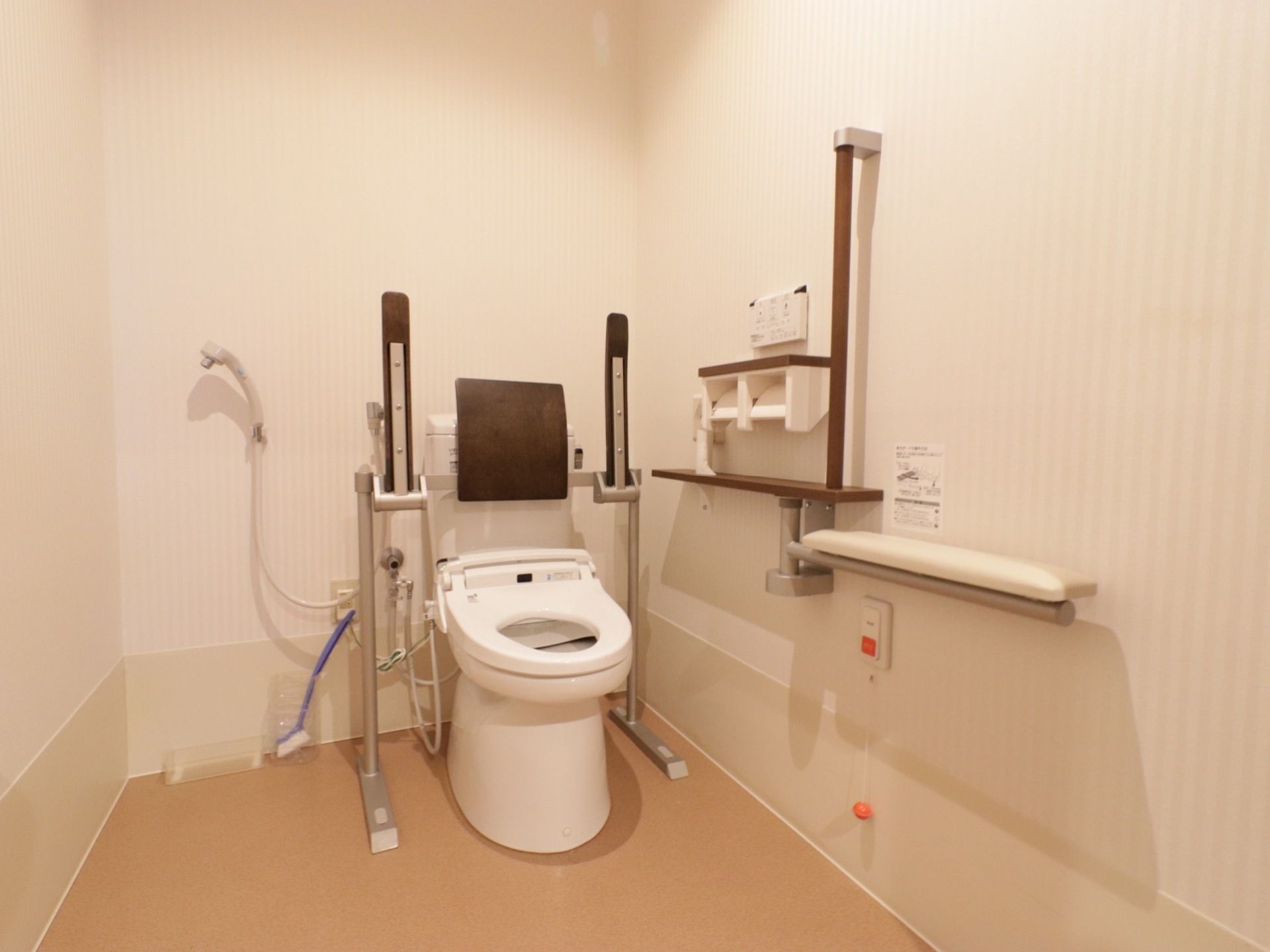 トイレ内はスペースが広くとられおり、温水洗浄便座の両側に立ち上がり用の手すりが備えられ、シャワーも完備されている。