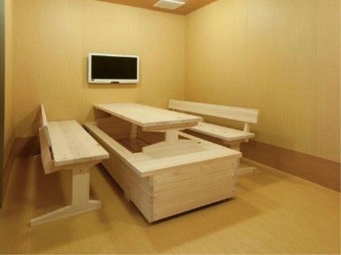 木目調の部屋に、木製の足湯の設備が置かれている。壁にはテレビが掛かっている。ゆったりと楽しめる空間である。