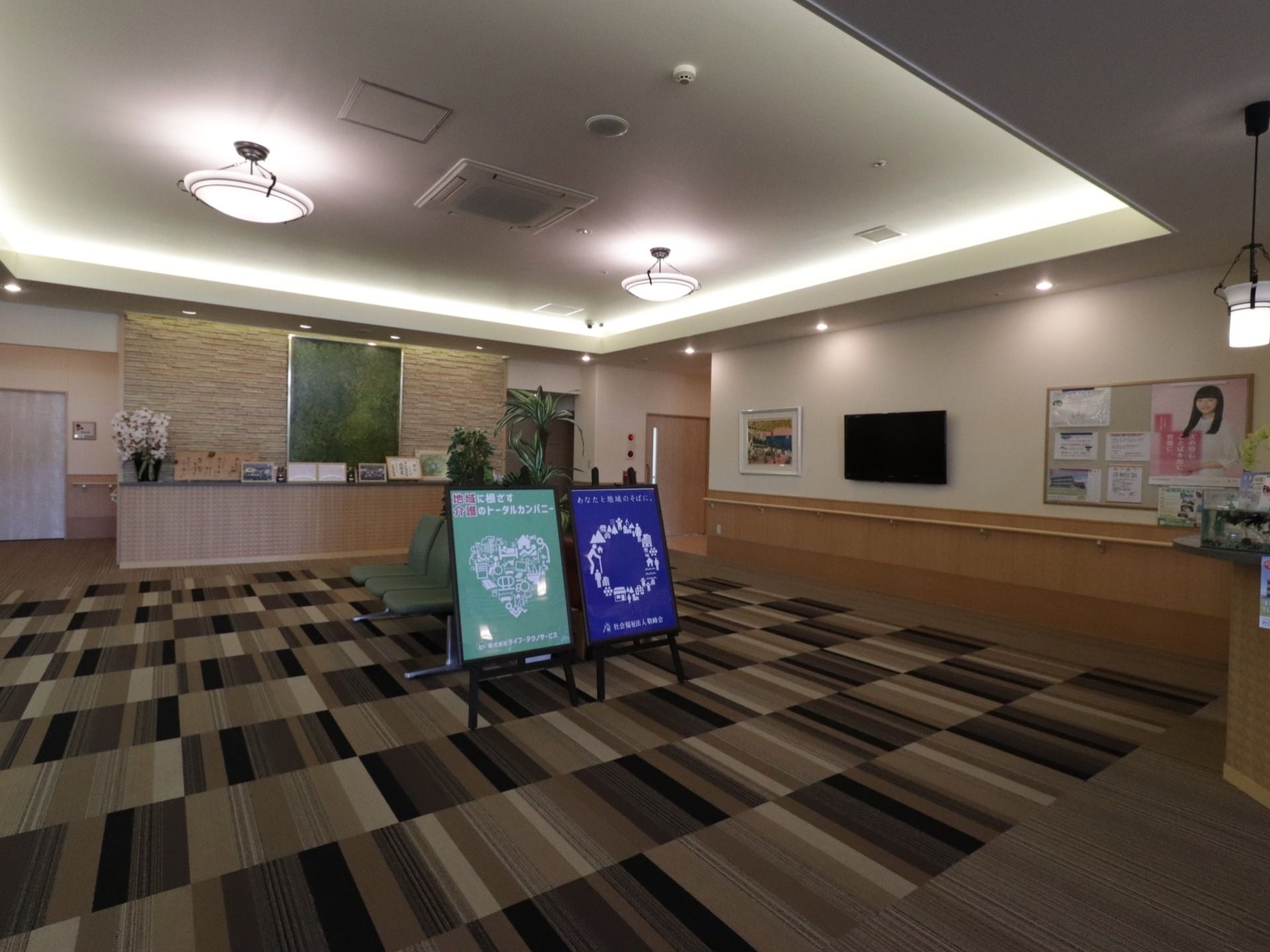 ブラウンを基調とした落ち着いた雰囲気のホール。壁には手すりが設置されている。フロアには椅子が置かれている。