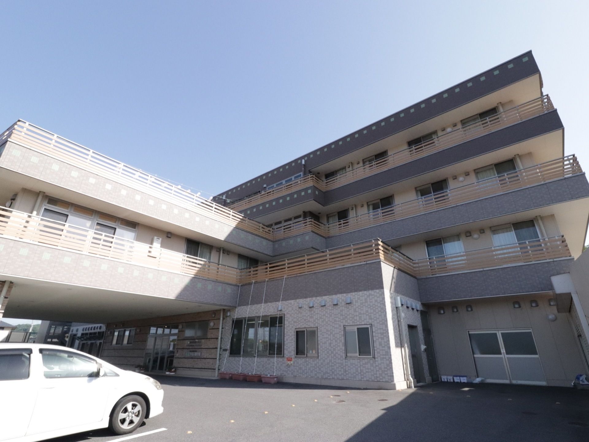ブラウンをグレーを基調とした外壁が落ち着いた雰囲気の４階建ての施設である。敷地はコンクリートで整備され、駐車場が完備している。