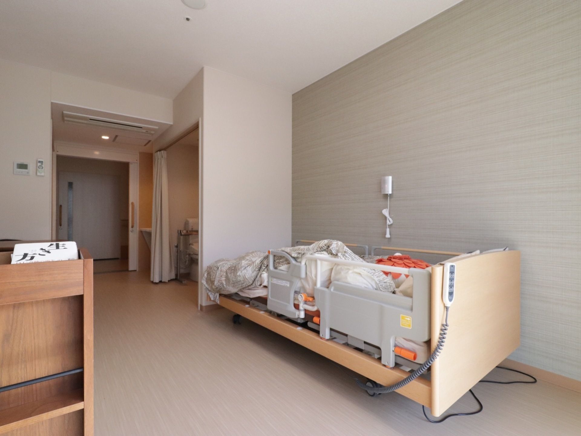 居室の床はフローリングで、出入り口やトイレ部分にも段差は一切ない。壁際に設置した電動ベッドにはフェンスを取り付けている。