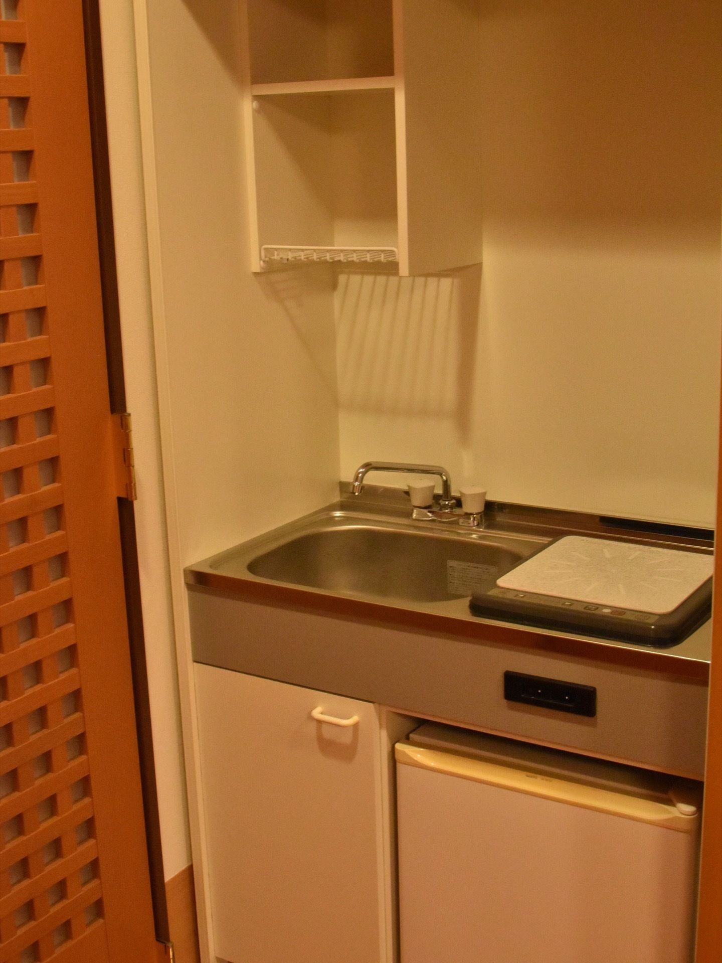 居室内のキッチン。流し台、冷蔵庫、収納がある。IH式ヒーターが採用されている。炎が出ないので安全である。
