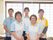 職員が4名カメラに向かって立っている。男女が2人ずつで交互に立っている。色違いのユニフォームを着用している。