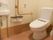 手すりがついた洋式トイレで、壁には緊急用のブザーが設置してある。トイレットホルダーが2つ壁についてある。独立した手洗い用の洗面台がある。