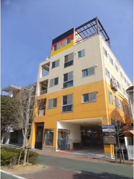 印象的な黄色の外壁で、遠くからでもわかりやすい建物である。１階部分には駐車場があるので、車での来訪も便利である。