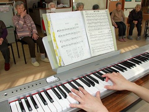 スタッフの弾くピアノに合わせて入居者様が音楽を楽しむ、施設のアクティビティ