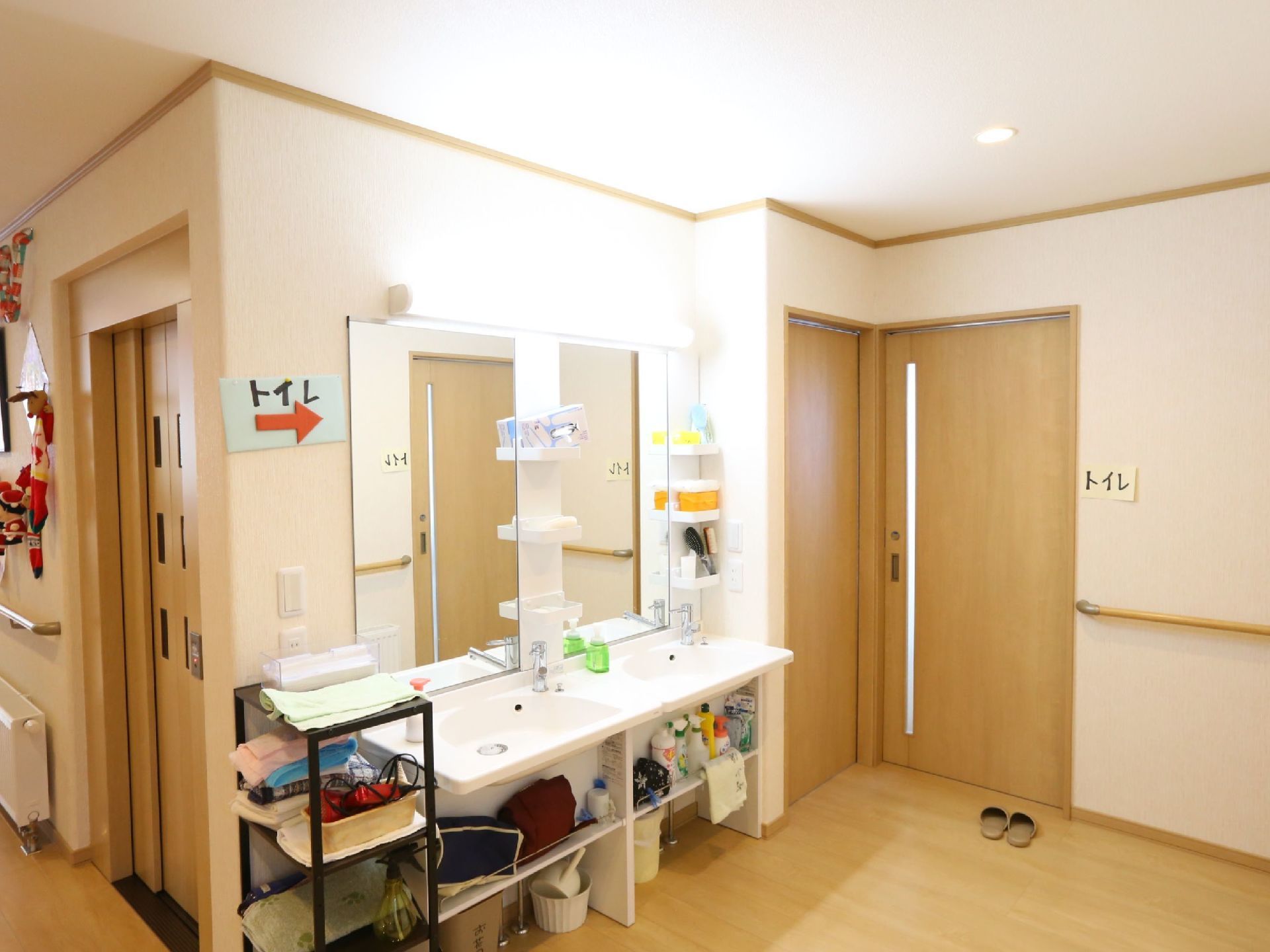 トイレの前には、２つの洗面台が設置されたスペースが設けられている。鏡や照明、収納棚が壁に備えつけられている。