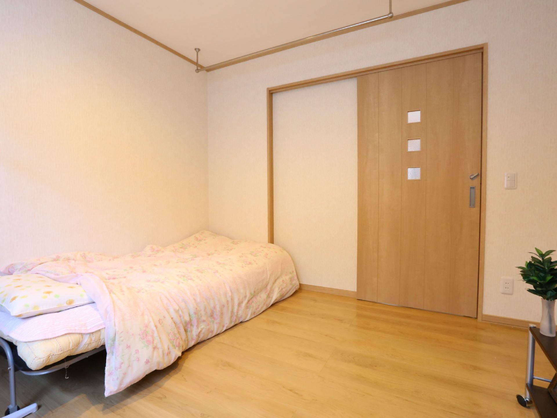 広めの間取りの居室である。壁際にベッドが配置されており、室内物干しが天井に設置されている。扉には、引き戸が採用されている。