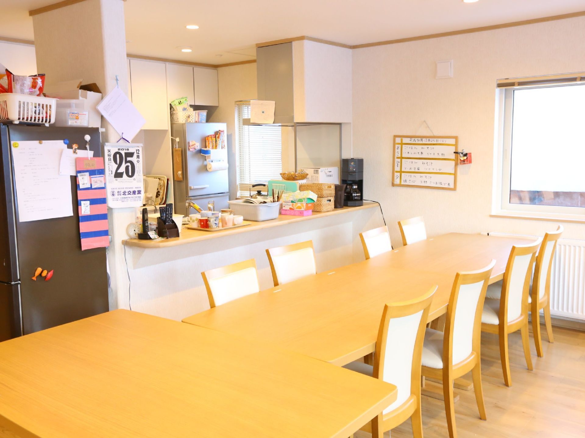 対面式キッチンが設けられた食堂である。椅子がセットされたダイニングテーブルが置かれている。壁際には、ヒーターが設置されている。