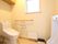 共有トイレには、洋式便器と男性用便器が設置されており、手すりやヒーターが完備されている。扉付き収納棚が壁に取りつけられている。