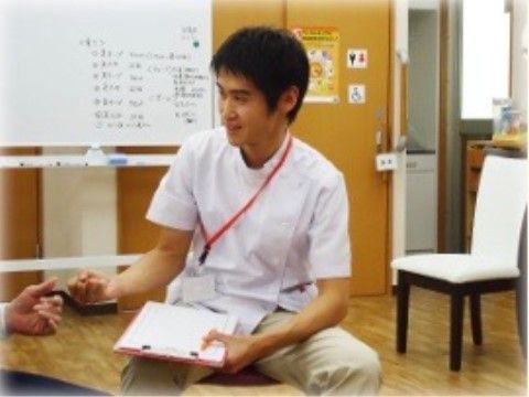 入居者様と会話をする、白衣を着て名札を下げた男性スタッフ