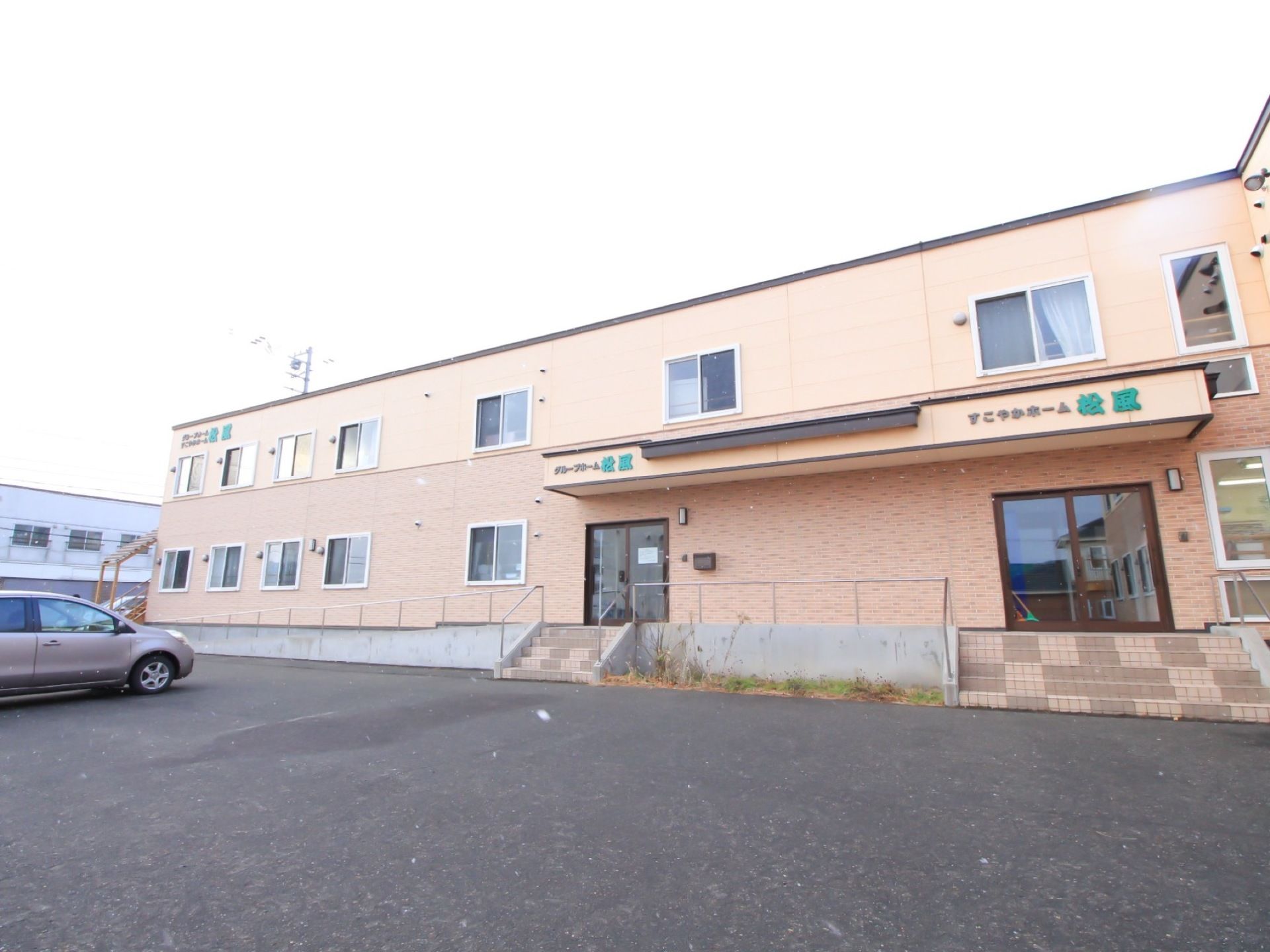 ２階建ての建物である。正面入口には階段のほか、スロープもあり、手すりがついている。広い駐車場が完備されている。