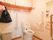 トイレの壁にある作り付けの棚は、白いカーテンで目隠しされスッキリとして見える。入口は間口が広く、出入りがしやすい。