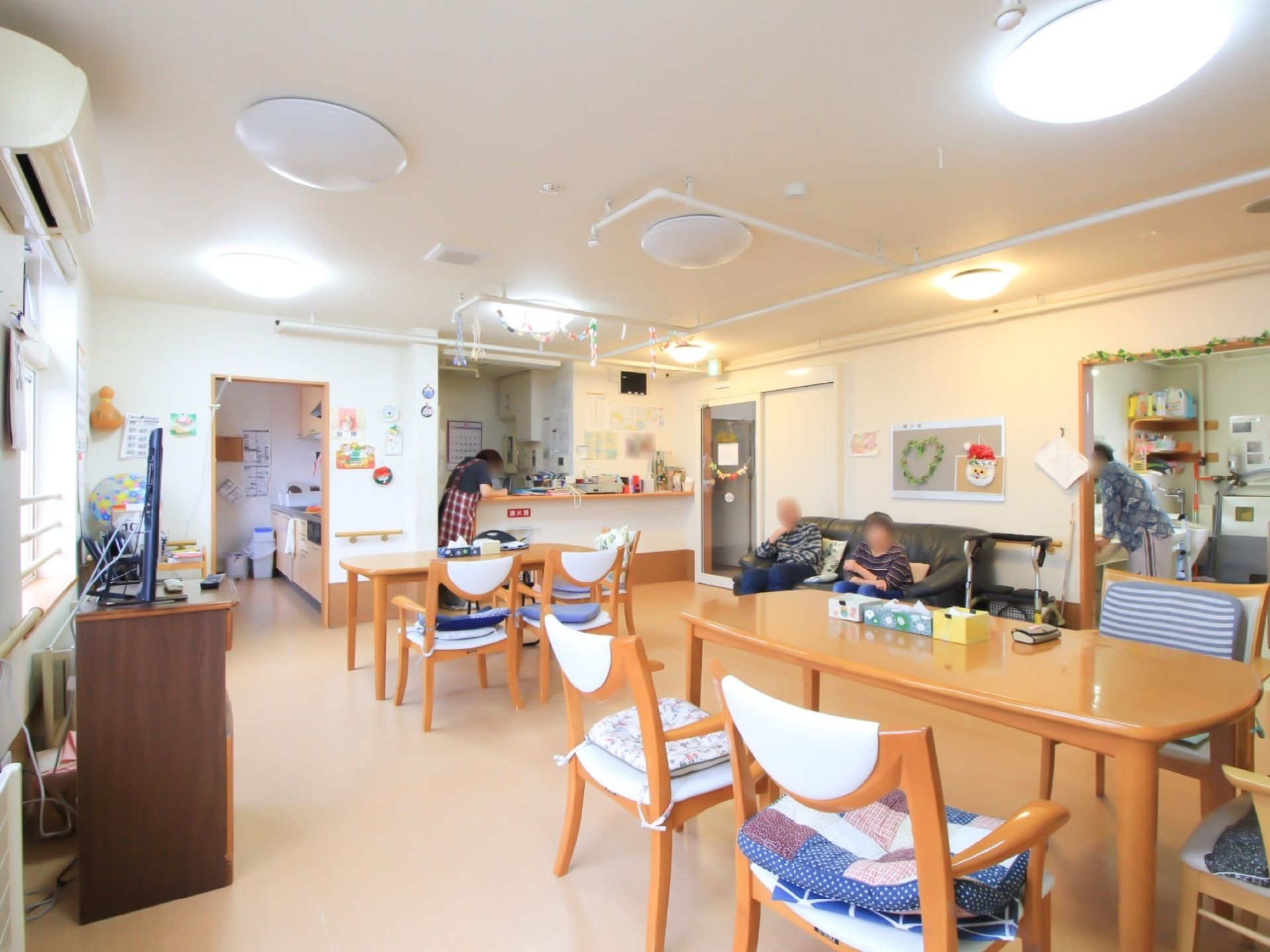カラフルな掲示物が飾られた、座布団のついた椅子の並んだ食堂