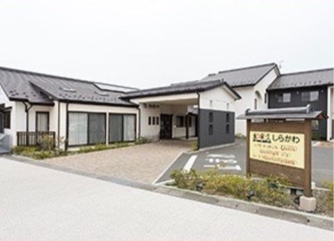 平屋の建物と2階建ての建物が併設されている。建物は黒と白を基調としている。歩道の近くに、施設名の書かれた看板が設置されている。