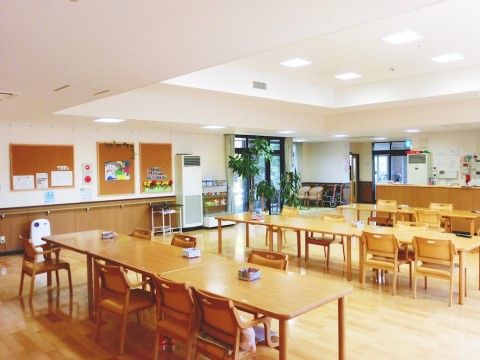 観葉植物が置かれ、壁には掲示物が張られた広々とした食堂