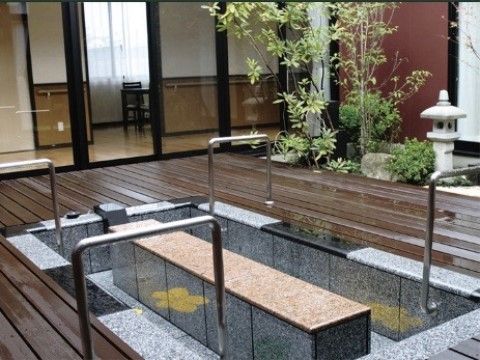 腰かける場所の脇にくるように手すりが設置されている。足湯の周りはウッドデッキになっていて、足湯自体は御影石調なので高級感がある。