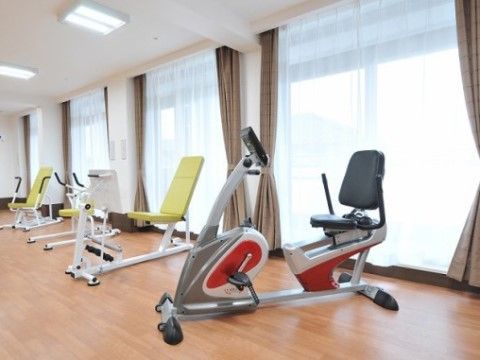 ペダルを漕ぐリハビリ機器などが並んでいる、明るい機能訓練室