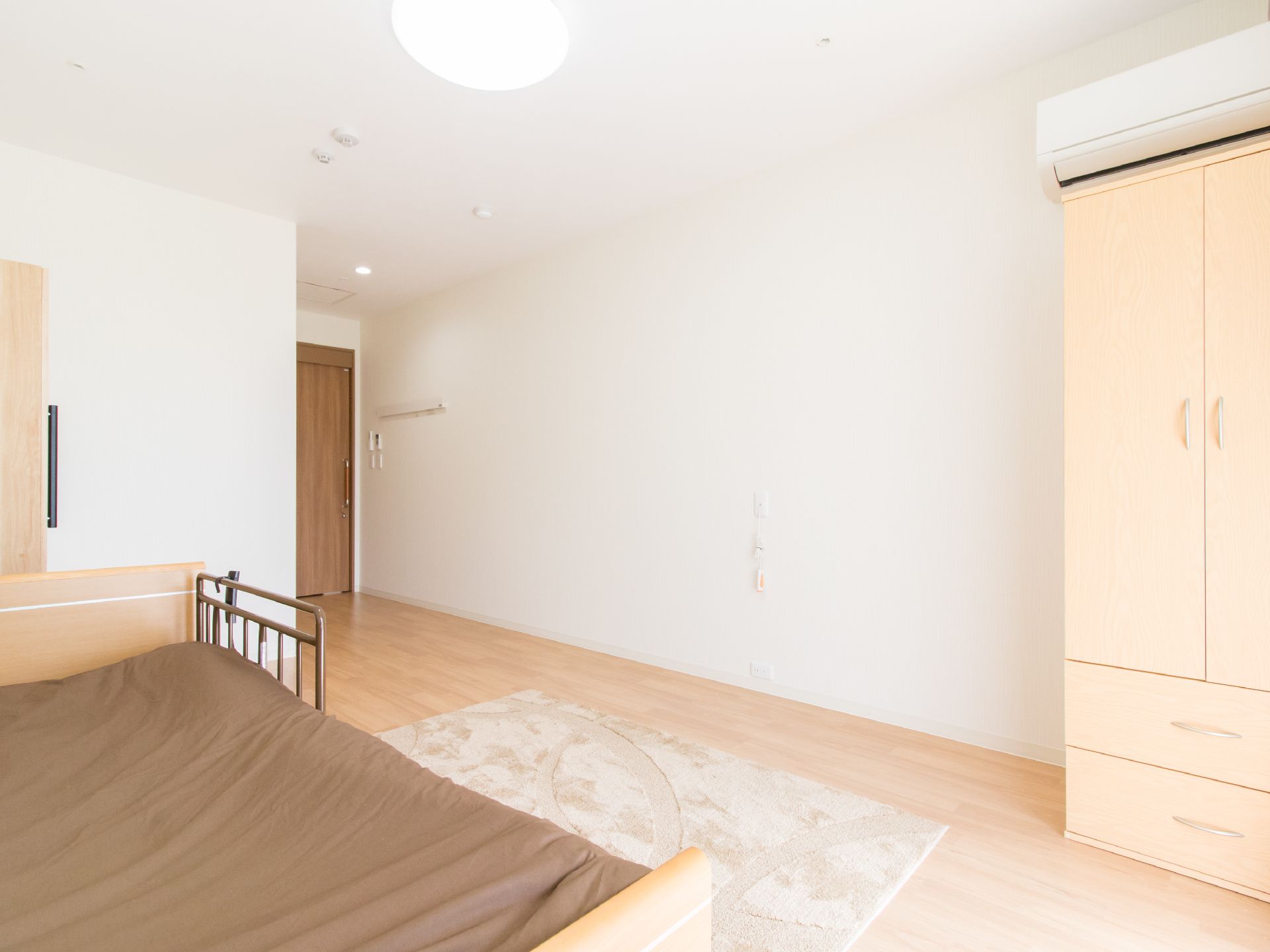 白い壁に木目調の床がモダンな雰囲気の居室。洋服ダンスと介護用ベッドが完備されているので持ち込む必要がなく便利である。