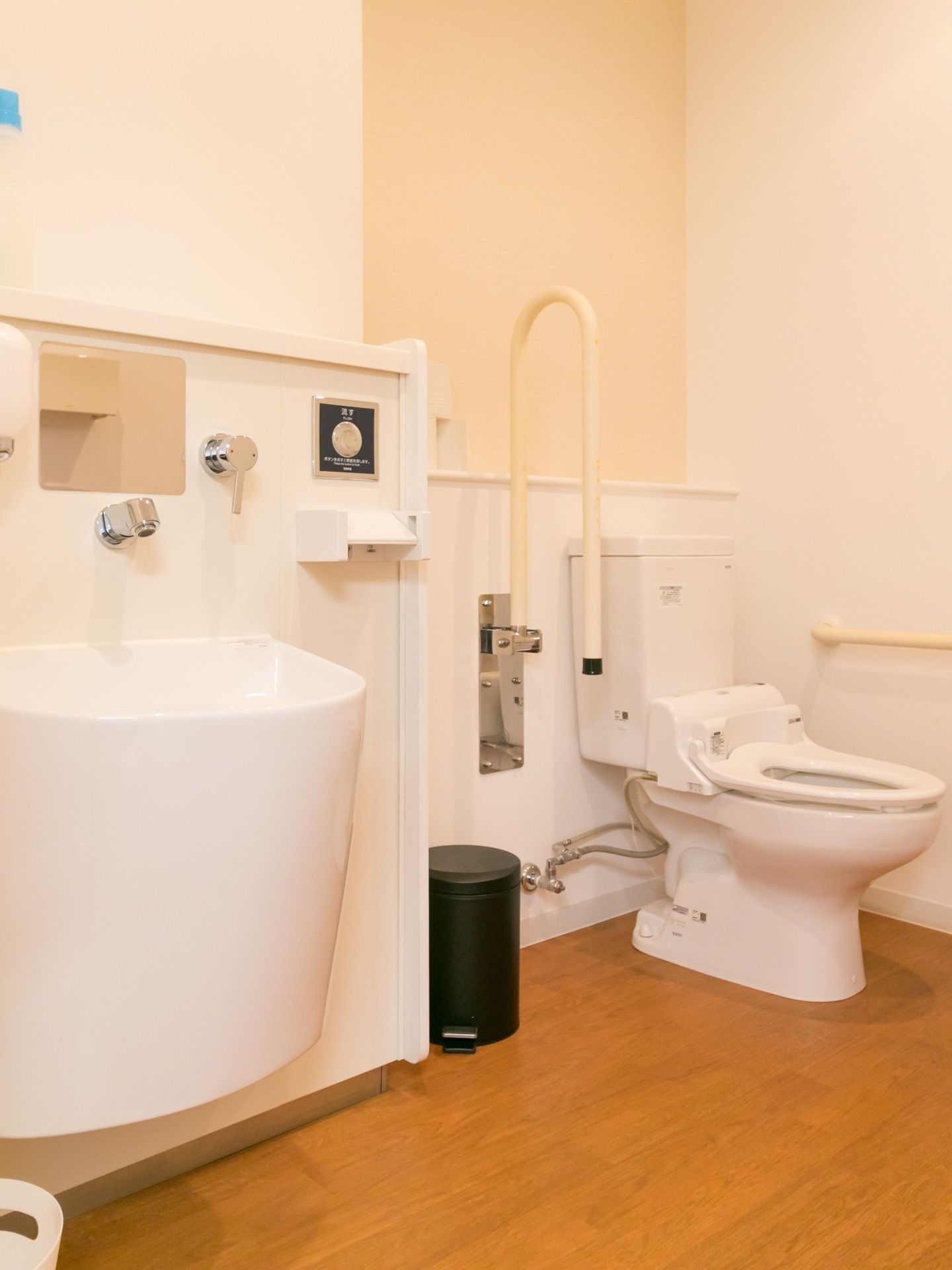 広々としたトイレスペースに洋式便器とオストメイト対応の設備を設置している。壁には手すりを取り付けている。