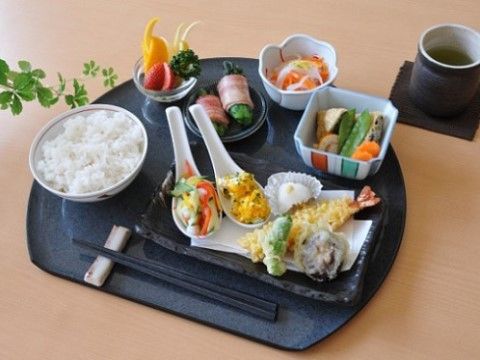ご飯や煮物、天ぷら、フルーツなどが並べられた、バランスの良い食事
