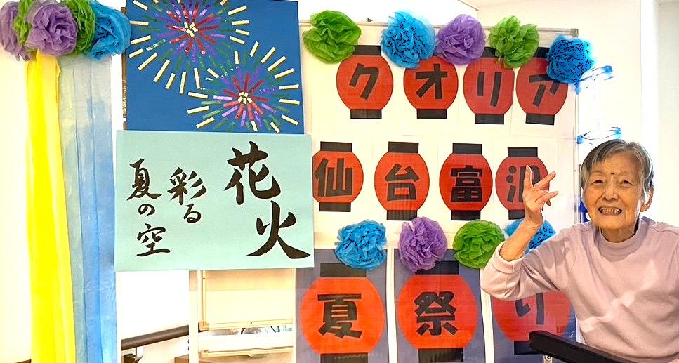 大勢の入居者様が椅子に座り、紙を見ながら歌を歌っている様子