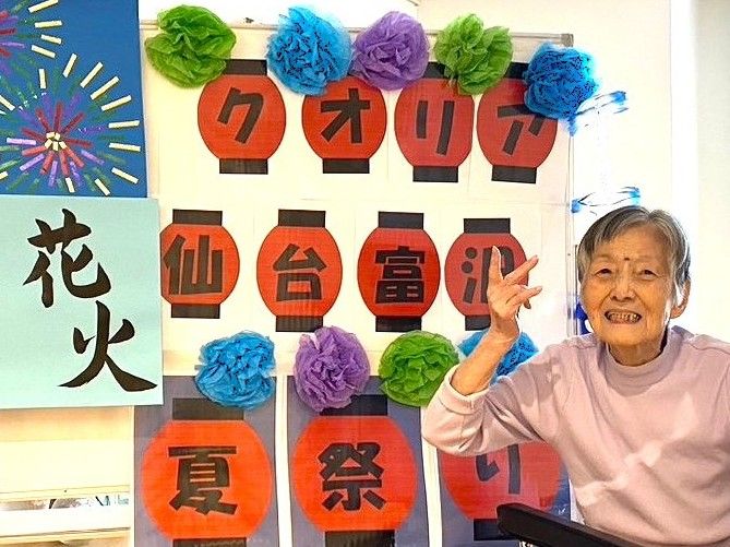 大勢の入居者様が椅子に座り、紙を見ながら歌を歌っている様子