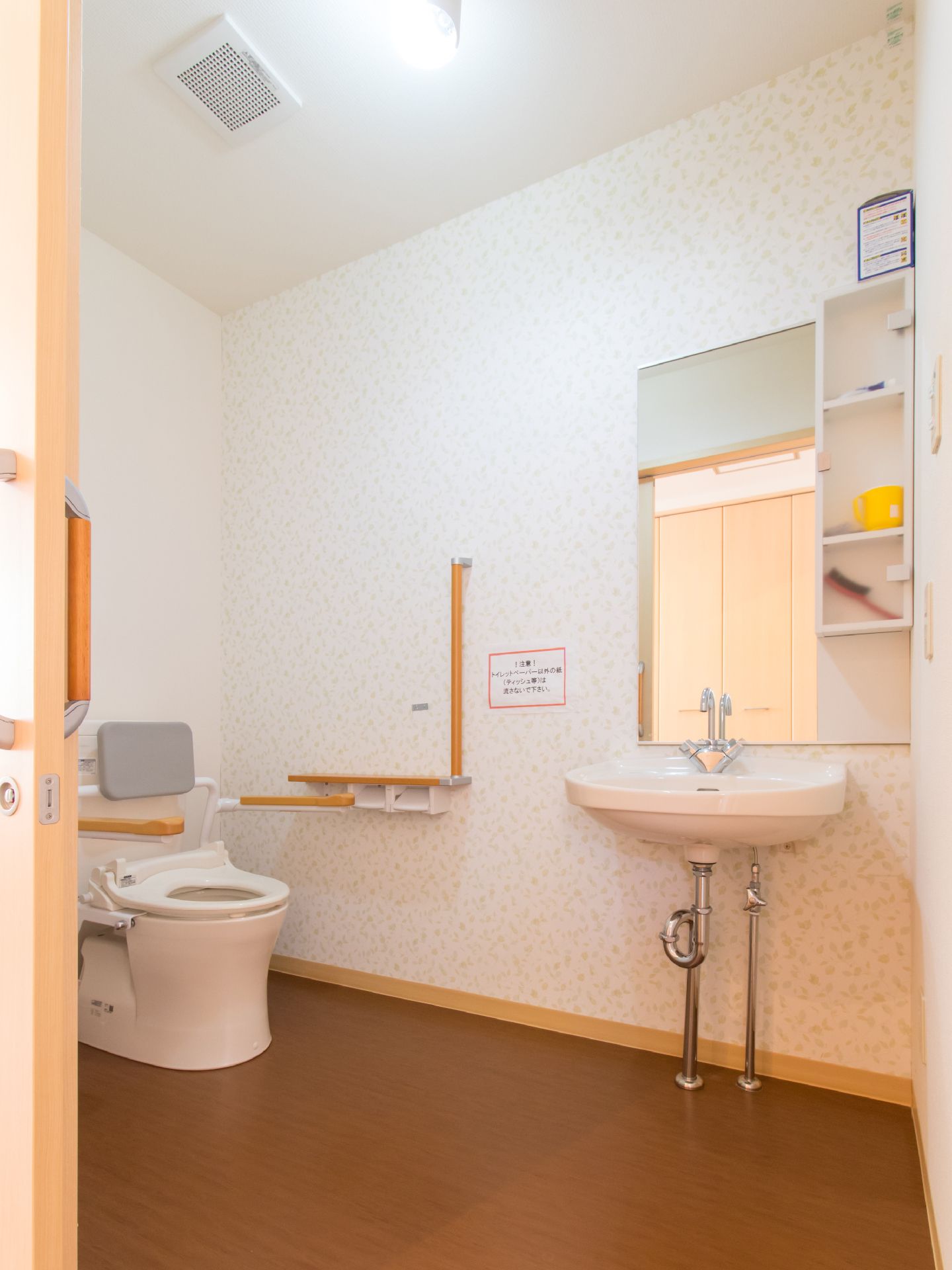 スライド式ドアで、広々としたスペースにトイレと洗面所がある。床はフローリング。換気扇が設置してある。