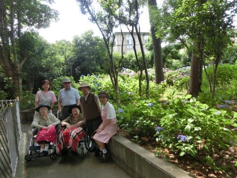 緑に囲まれた環境で散歩を楽しむご入居者様とサポートスタッフ。