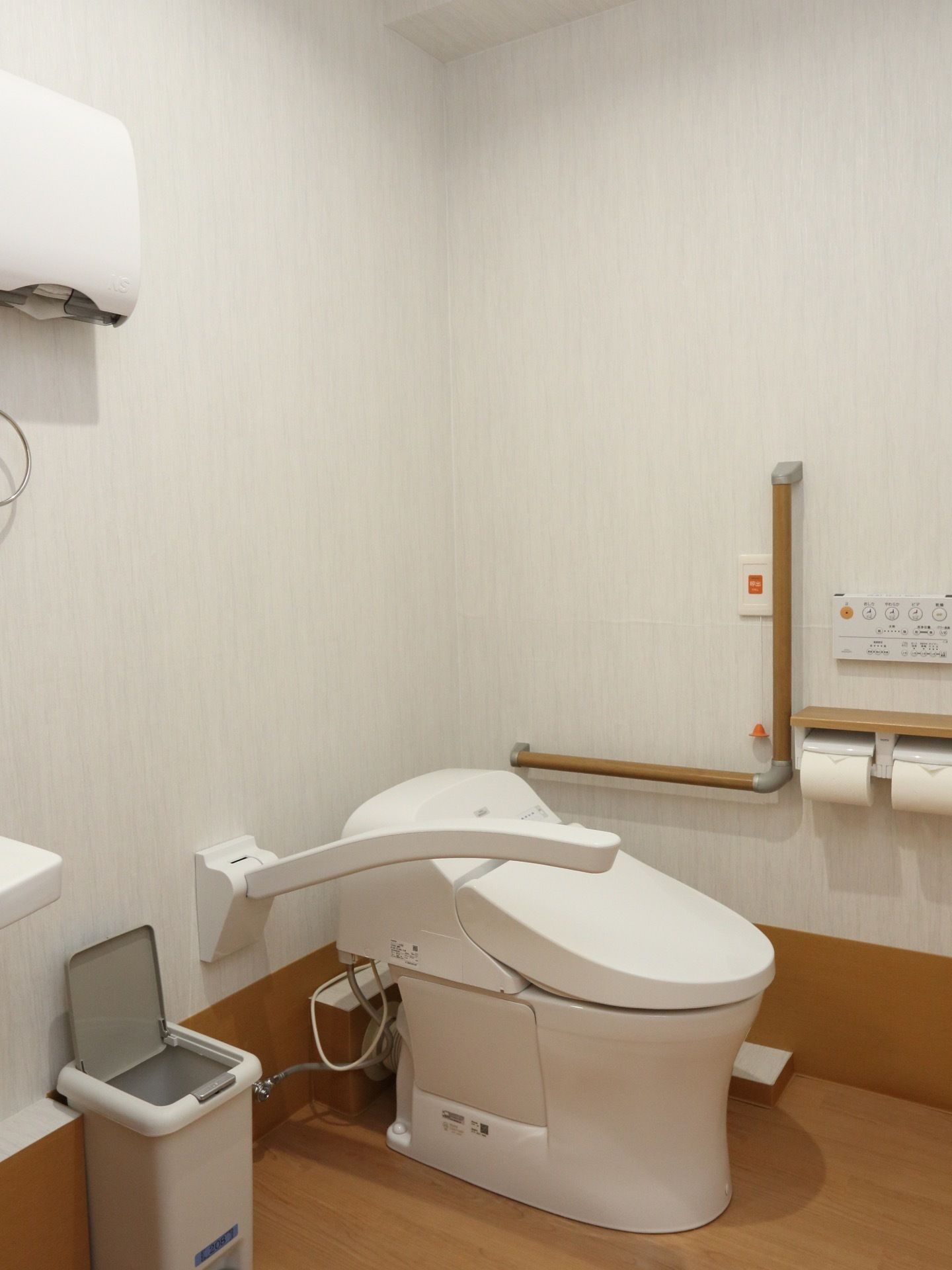 便器とタンクが一体化したコンパクトなトイレである。周囲に可動式のアームレストと手すりが設置され、ナースコールも付いている。