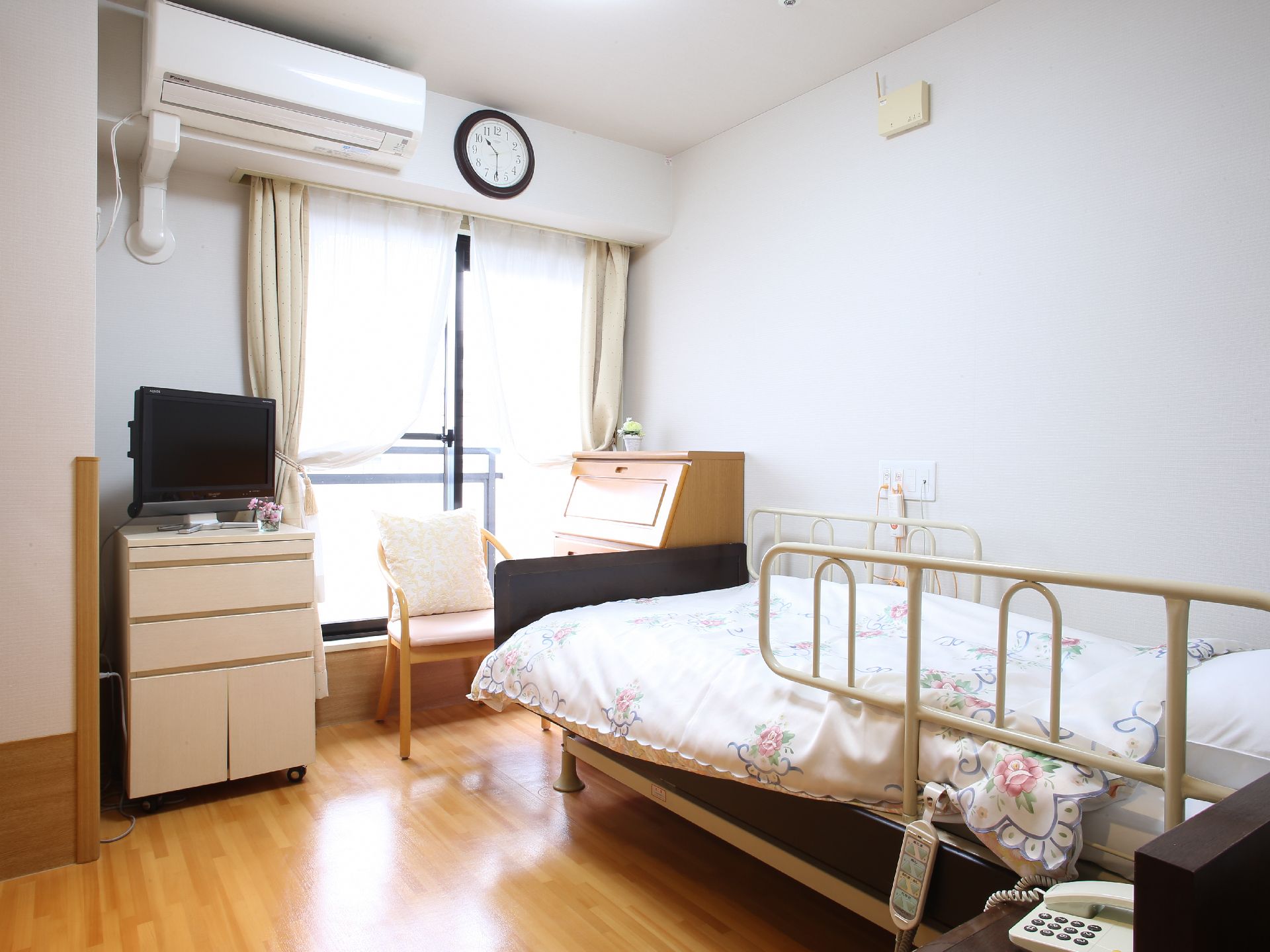 シングルルームには介護ベッドやエアコン、テレビ、電話機などが完備されている。家具も一式揃えられている。