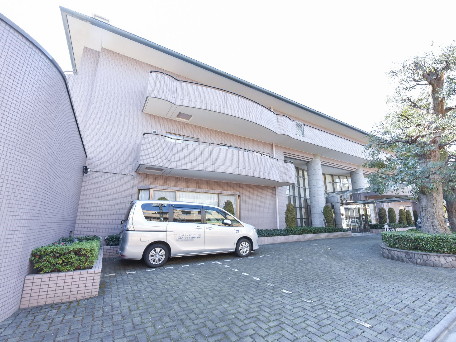 3階建ての施設前には駐車スペースがある。エントランスには屋根があるので、濡れることなく送迎バスや車への乗り降りができる。