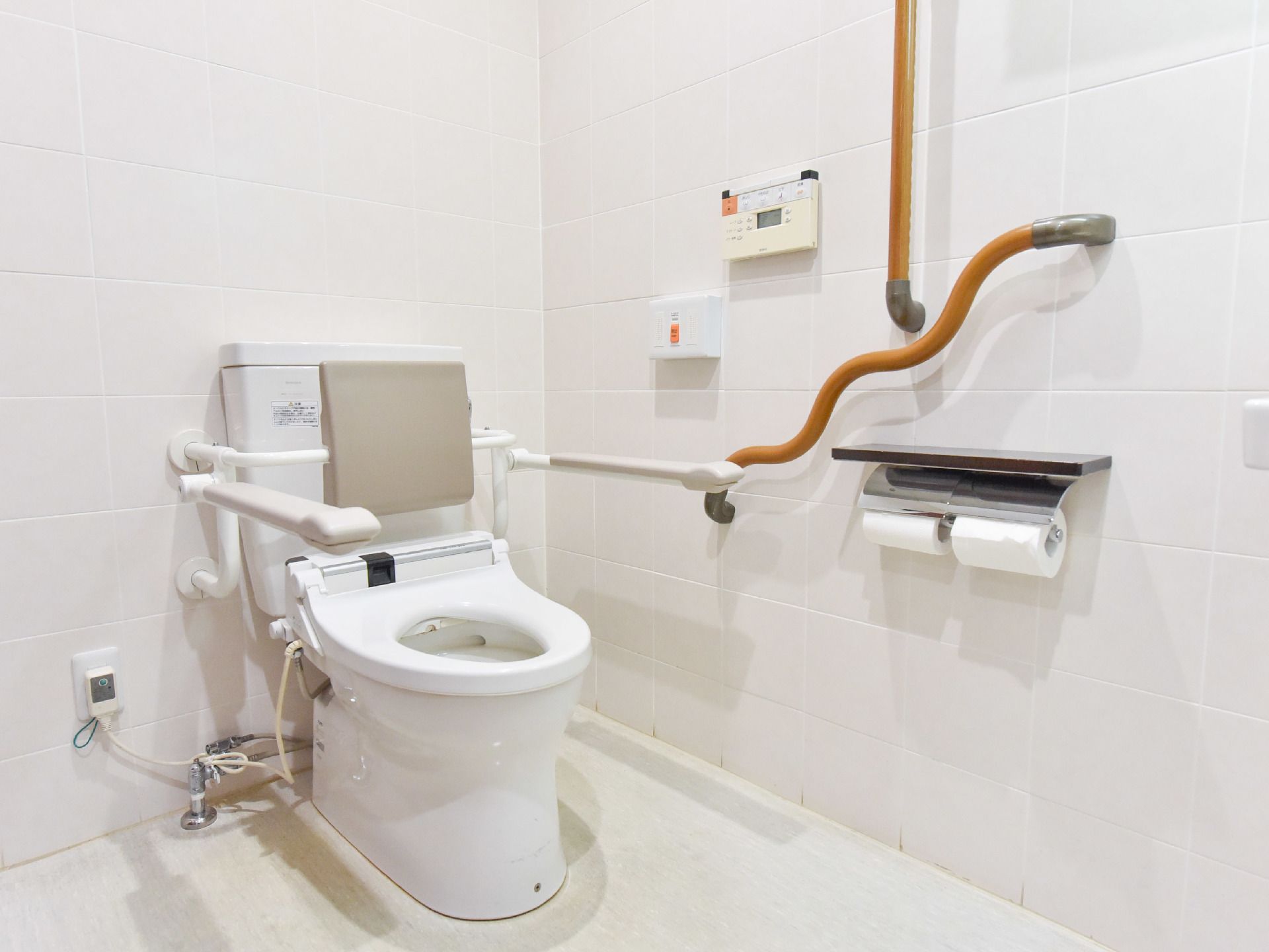 温水洗浄トイレには立ち座りをサポートする手すりが設置されている。また背もたれ用のパッドも付いている。