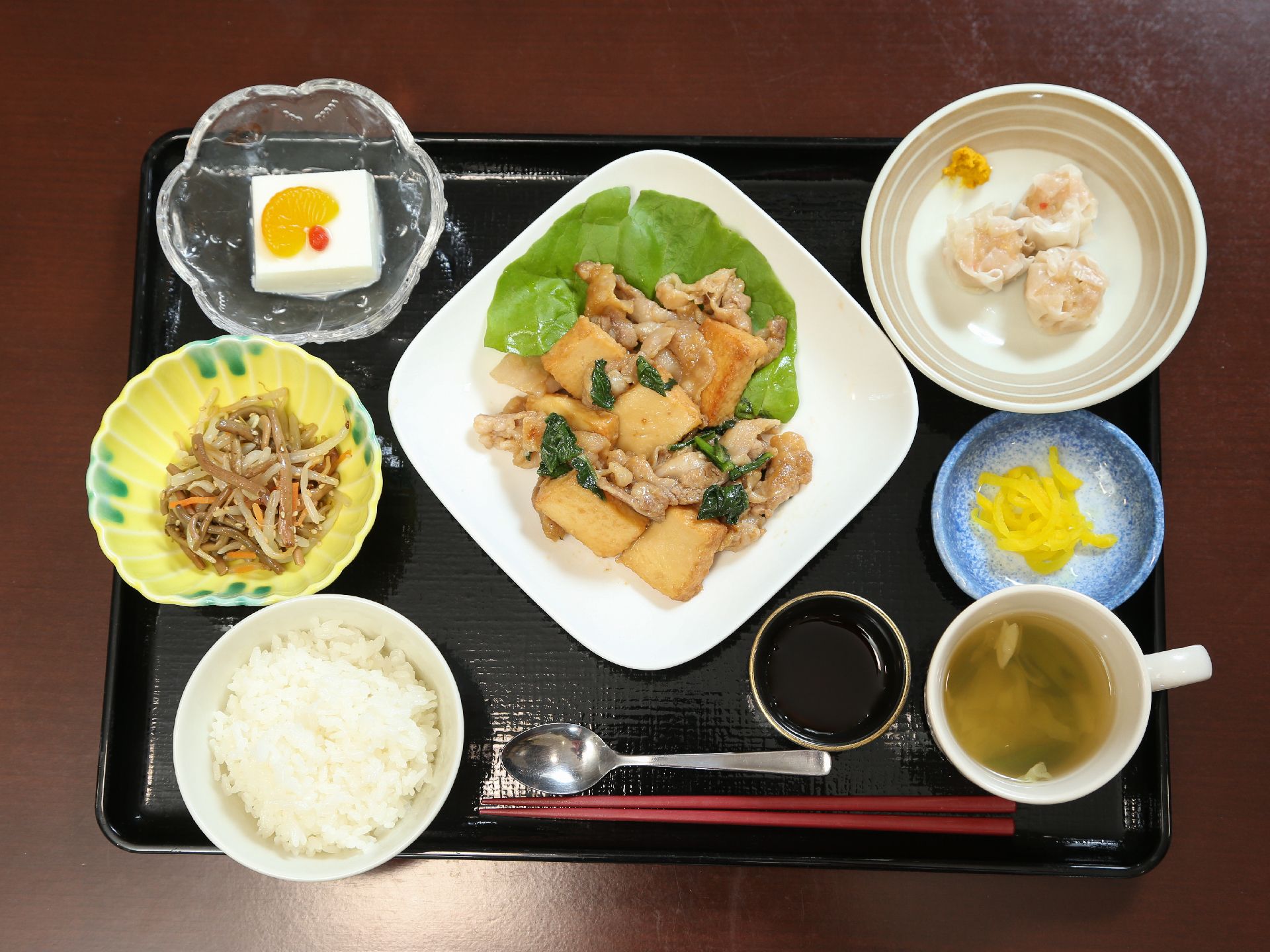 野菜と肉の炒め物、シュウマイ、きんぴらごぼう、豆腐、汁物、ご飯など6品、栄養バランスを考慮して用意されている。