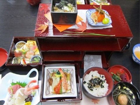 料理の周りに赤い紅葉が飾られた刺身の定食