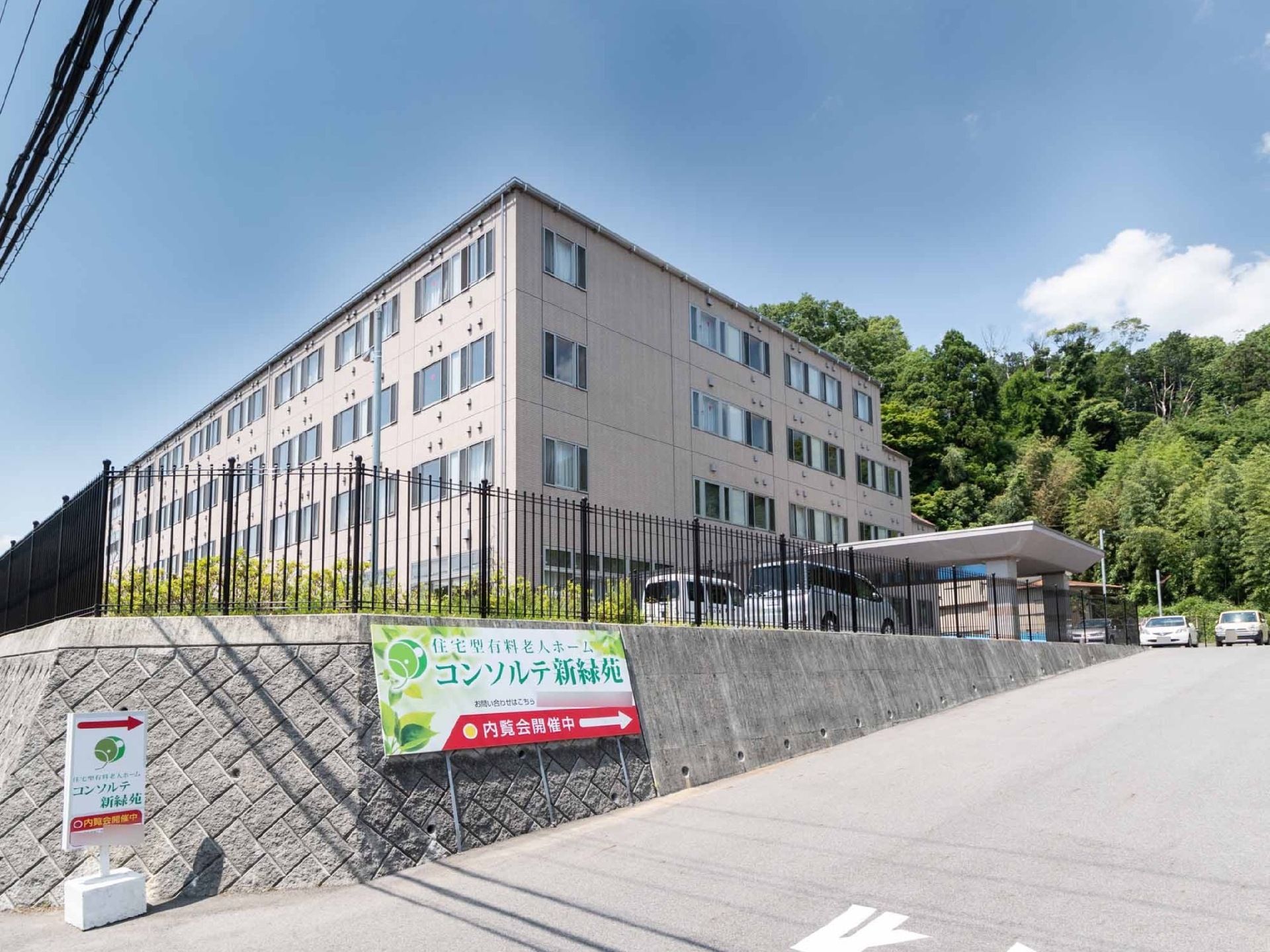 施設は高台に建っており、石垣部分に施設名の看板が取り付けられている。玄関前まではスロープになっている。