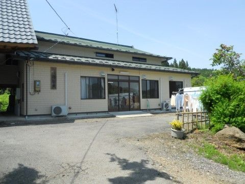 民家のような外観の建物。入り口周りに段差はなく、扉はガラス張りになっている。駐車場が用意されている。