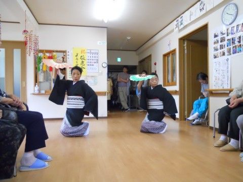 着物を着た2人の女性による日本舞踊を、椅子に座って見ている入居者様