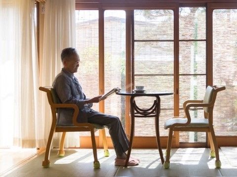 日当たりの良い窓辺の椅子に座って読書をしている入居者様