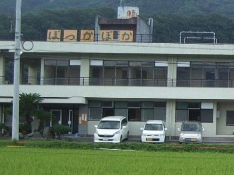 施設は、自然豊かな地域に位置している白い外壁の２階建ての建物