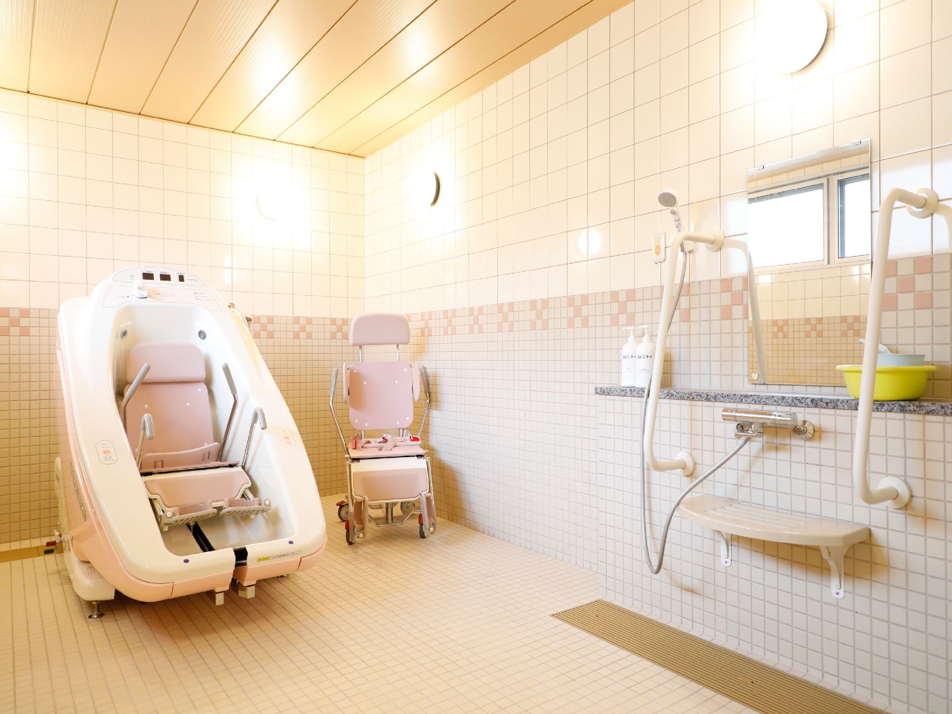 薄いピンク色が基調の浴室に機械浴槽が設置されている。体が不自由な方も楽に入浴ができるようになっている。
