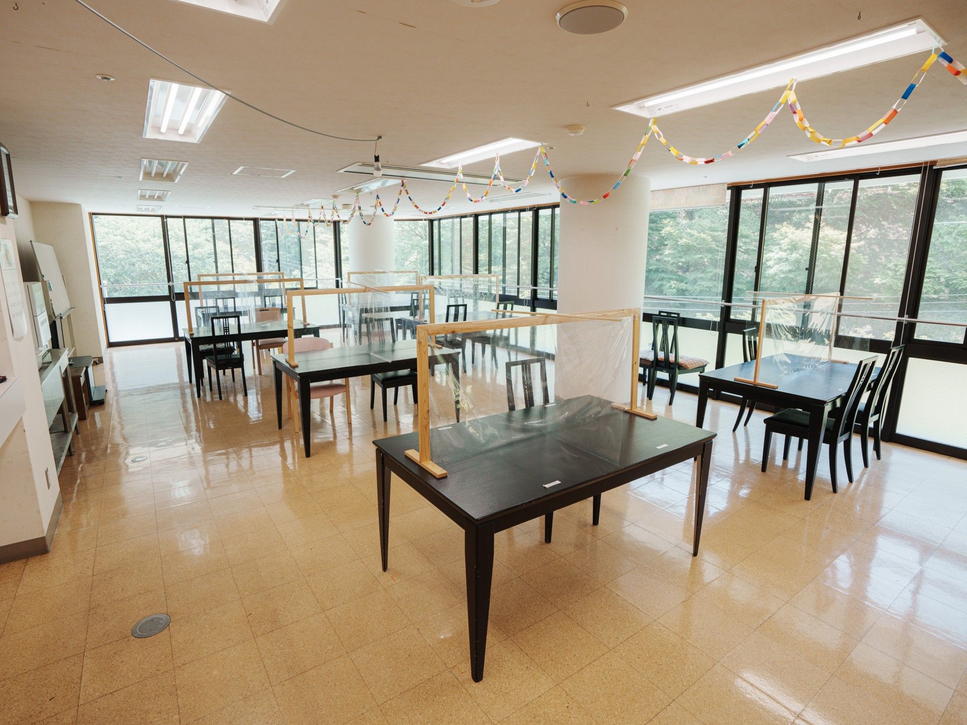 緑豊かな道を散歩する車椅子の入居者様と2名のスタッフ