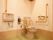 清潔なトイレには、温水洗浄便座付きの便器と手洗い器が設置されている。便座の両脇には手すりが設置されている。