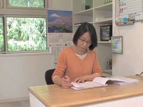 スタッフルームに置かれた事務机で書き物をしている女性スタッフ