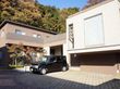 一軒家風の建物が2つあり、つながっている。建物前にバリアフリーの駐車スペースがあり、黒い車が1台駐車している。