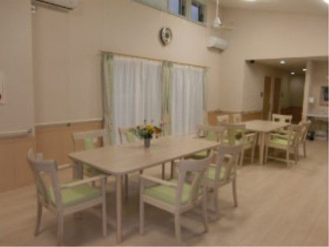 広々とした空間にナチュラルな色合いのテーブルと椅子が置かれたリビング