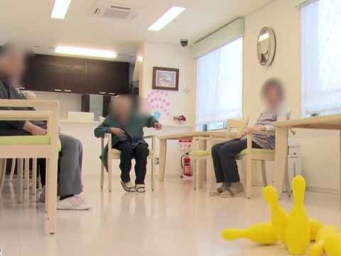 広く明るいリビングでレクリエーションに興じる３人の入居者様
