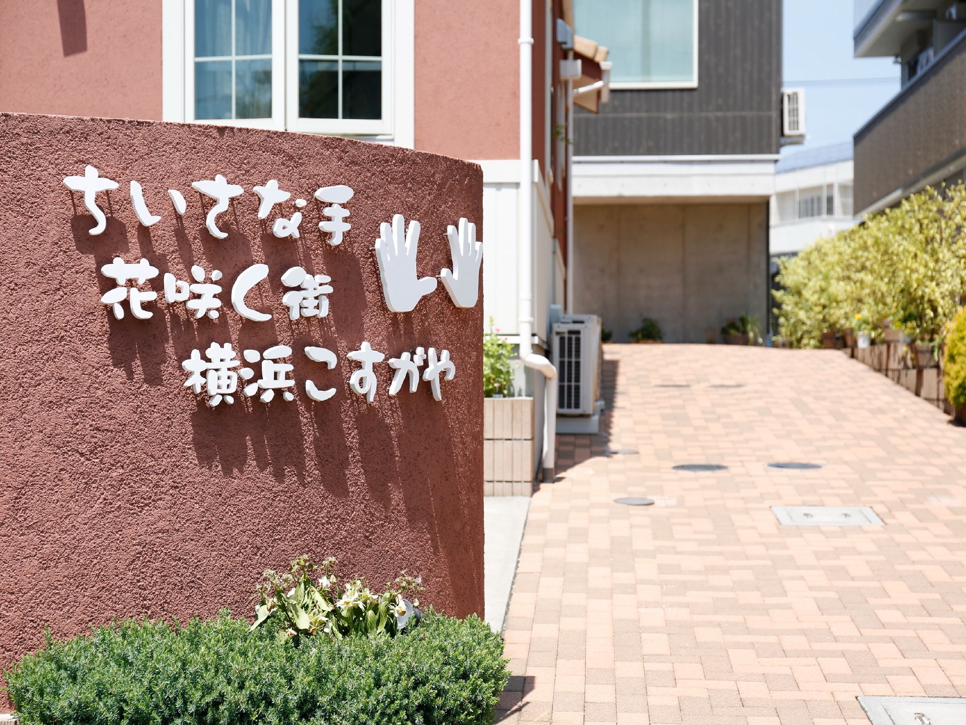グループホームの表札は、外観に合わせて褐色で丸いデザインに。ロゴマークになっている子供の手は実際にかたどったものです。