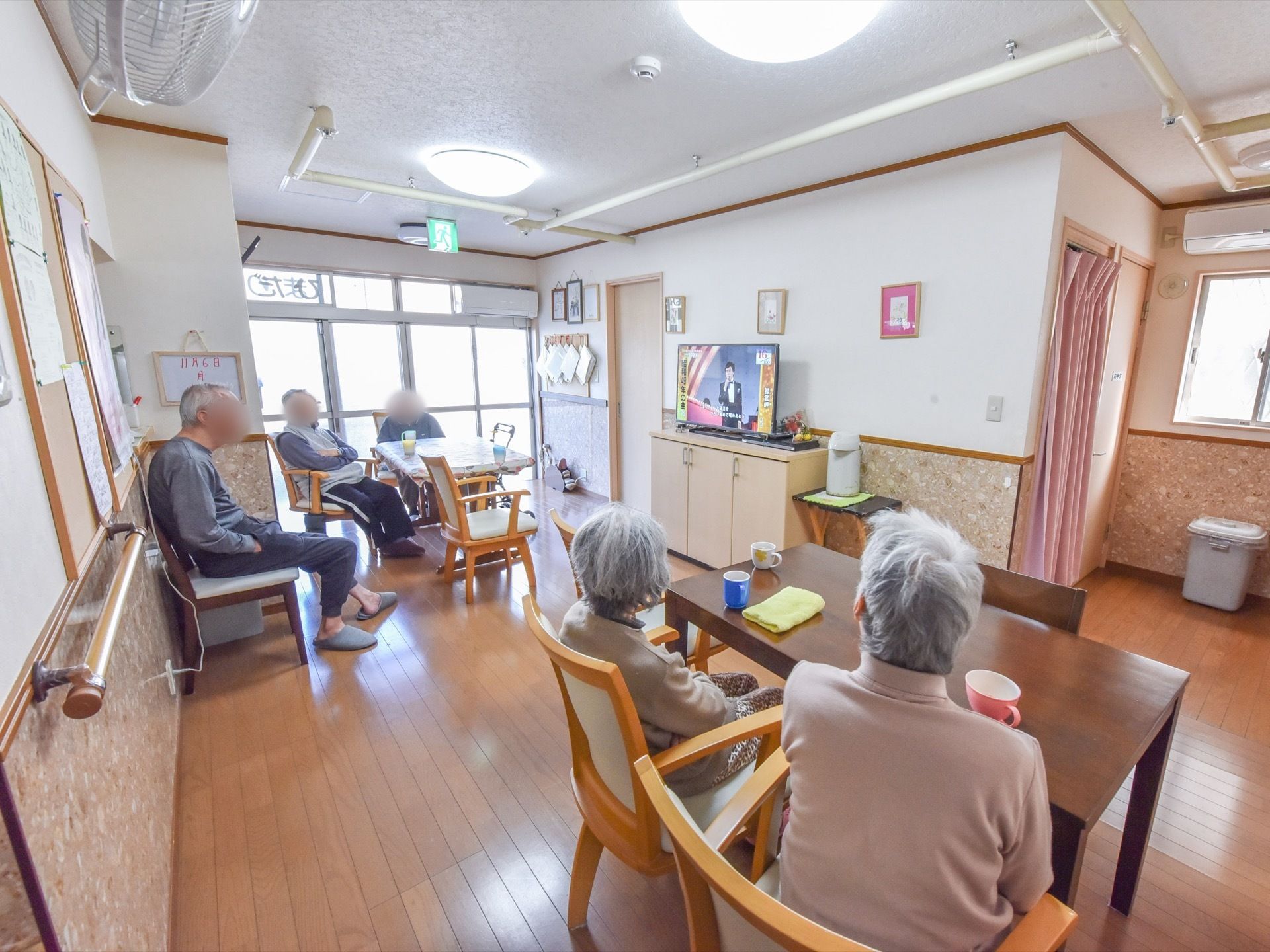 大型テレビとその横にポットが完備されている。談笑やテレビ鑑賞を楽しむことができる。テーブル間のスペースを確保している。