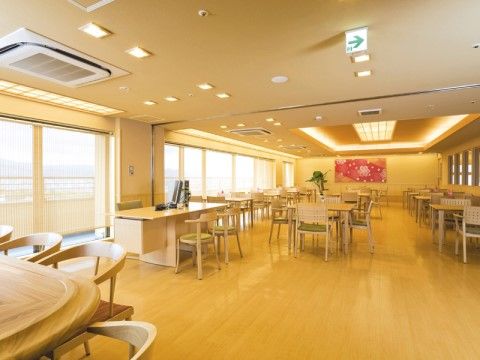 窓から明るい光が差し込む部屋である。窓からは街並みも一望できる。室内には木調の家具がきれいに配置されている。